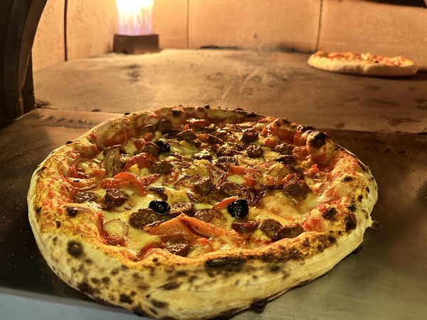 Pizza polpettes devant le four en flammes